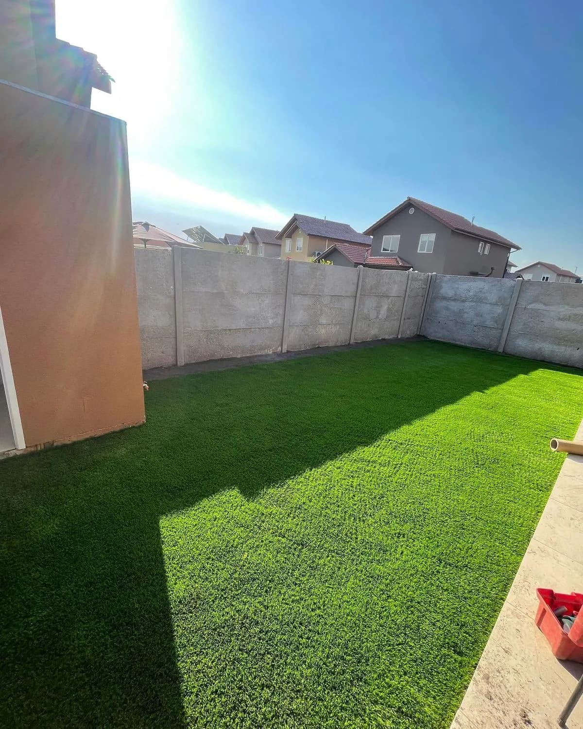 Patio cubierto de pasto sintético instalado de muro a muro, en un día despejado